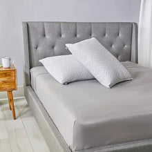 Two geometric pattern throw pillows folded on a gray bedspread