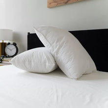 White pillows stacked on a bedspread with visible seam lines