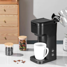 Black matte single-serve coffee maker with brew area and white mug on base