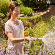 Lime-green garden hose with spray nozzle, misting plants from a handheld grip