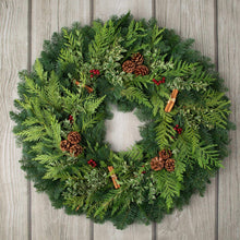 Evergreen wreath with pinecones, cinnamon sticks, and red berry accents