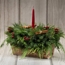 Evergreen centerpiece in birch log with red candle, pinecones, and cinnamon sticks
