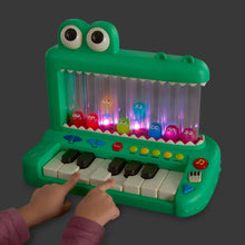 Green crocodile pop piano toy with lit character drums, white keys, and dark buttons