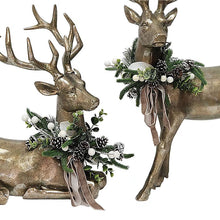 Pair of holiday deer ornaments close-up: bronze deer with pine wreaths and ribbon bows