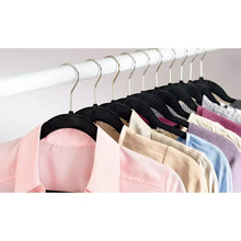 Set of black velvet hangers with metal hooks holding assorted shirts