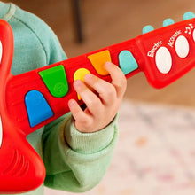 Close-up of red toy guitar neck with colored buttons and play labels