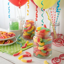Gummy candy worms in a clear jar with red, yellow, and green pieces