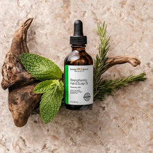 Hair and scalp oil bottle with rosemary sprigs and mint leaves, amber glass and black dropper