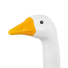 White goose statue head with yellow beak and black eye.