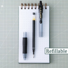 Retractable black fine-point gel pen with refill parts on a notebook