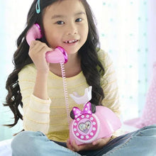Smiling child holding pink Minnie-style rotary phone toy with heart light panel