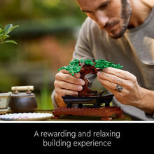 LEGO Icons bonsai tree set being assembled, with hands holding green branches over stand
