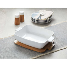 White ceramic oven-to-table serving dish with acacia lid resting on wood board