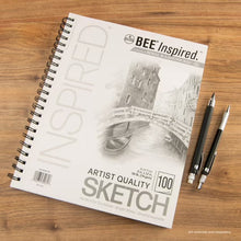 Sketching paper pad on wood surface, white Bee Inspired cover with Sketch 100 label