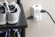 White wall outlet tap with cords and adapters plugged into grounded side outlets