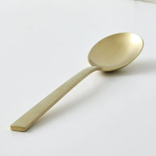 Gold stainless steel spoon with ridged handle and oval bowl