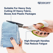 Office scissors cutting folded blue denim; white handle with green finger loop
