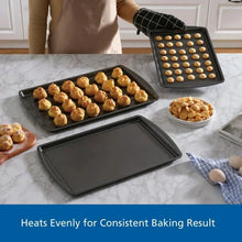 Gray nonstick baking tray holding baked cookies, with other trays from the set