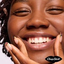Woman wearing lip balm, smiling with ChapStick on lips