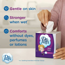 Hand holding a white facial tissue with a purple Ultra Soft tissue box
