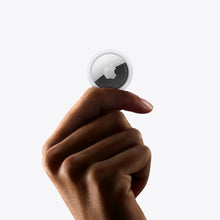 Apple AirTag tracker in a white housing held in a hand
