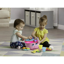 Toy picnic basket with pink face and purple handle while two toddlers play