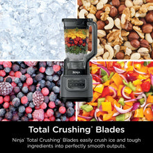 Dark gray blender with clear pitcher filled with mixed vegetables and herbs