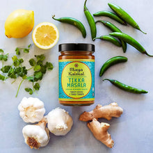 Tikka masala simmer sauce jar surrounded by ginger, garlic, lemons, and green chiles