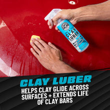 Hands using clay lube spray and yellow clay bar on a red car panel