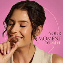 Person holding a wrapped LINDOR chocolate truffle near their mouth