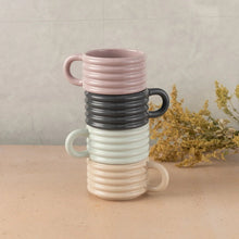 Ceramic ribbed stackable mugs in pastel pink, dark gray, and cream