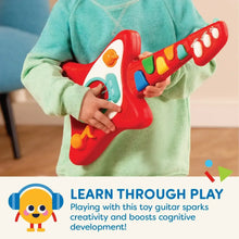 Red toddler guitar with colored buttons and strumming strings in child’s hands