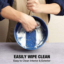 Blue speckled nonstick saucepan being wiped clean with cloth inside