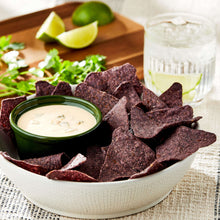 Queso blanco dip in green-lidded bowl with tortilla chips and lime wedges