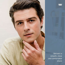 Young man with white shave cream on cheek and chin, hand supporting face