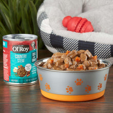 Wet dog food in bowl with stew pieces, beside a Country Stew cuts-in-gravy can.