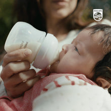 Philips Avent Natural baby bottle with pink accents, being used during baby feeding