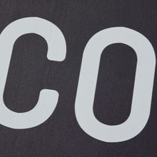 Black indoor laundry runner rug close-up of large white 'CO' lettering