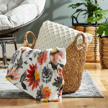 Natural woven water hyacinth boat storage basket holding a floral throw blanket