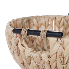 Close-up of braided woven water hyacinth bowl edge and wooden-look handle bar