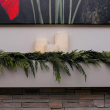 Green evergreen cedar garland laid across a fireplace mantel with cascading ends