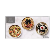 Three white porcelain cereal bowls on display with plated cereal