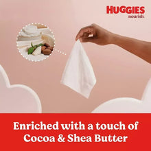White baby wipes on a surface with a hand pulling one out