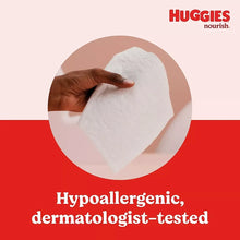White baby wipe sheet held up by a hand