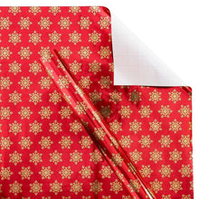Red holiday wrapping paper with repeating gold snowflakes and blank white sheet