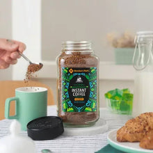 Instant coffee jar with black lid and green instant coffee label on a kitchen table