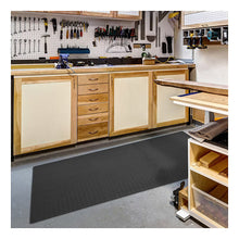 Interlocking dark gray foam floor tile mat with diamond plate texture under workbench