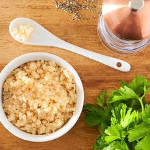 Minced garlic in water in bowl and spoon with parsley sprigs