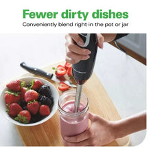 Immersion blender blending strawberries in a glass jar