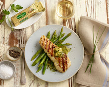 Garlic and herb butter stick near a plated chicken breast with asparagus and lemon